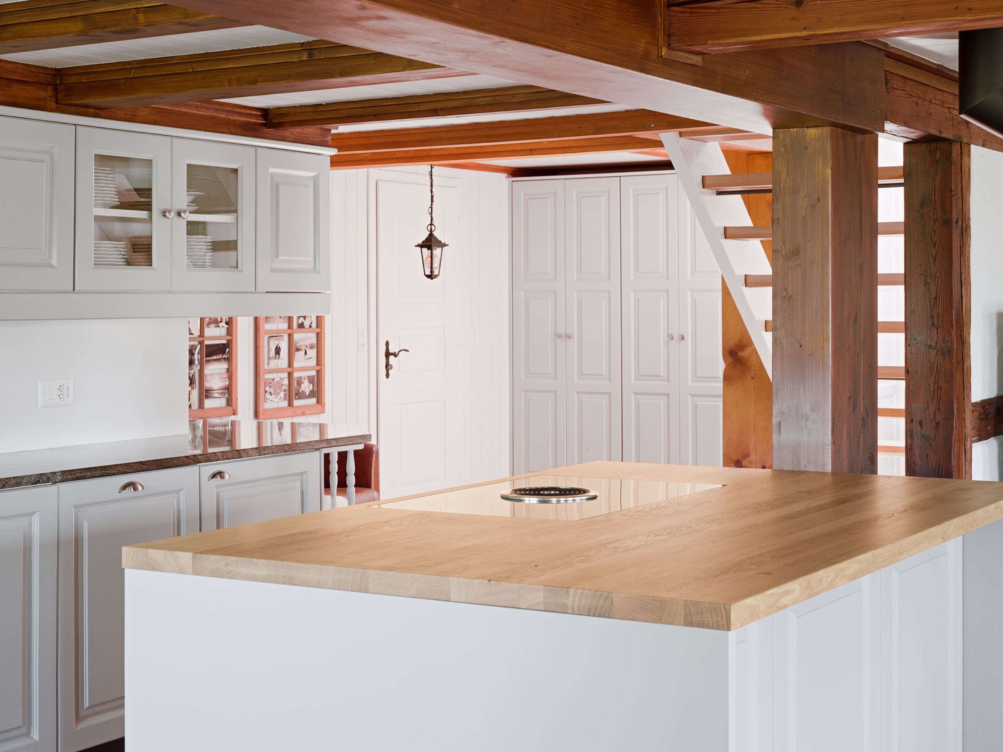 Landhausküche mit Holzarbeitsfläche, Holzbalken und Treppe